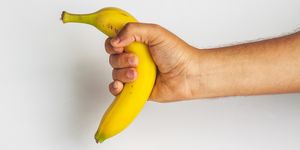 close up of man holding banana against white background