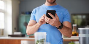 close up of man using fitness tracker to count calories for post workout juice drink he is making