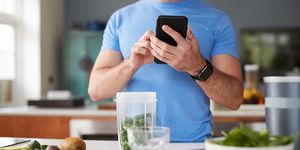 close up of man using fitness tracker to count calories for post workout juice drink he is making