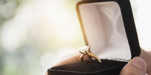 close up of mans hand holding open box with engagement ring
