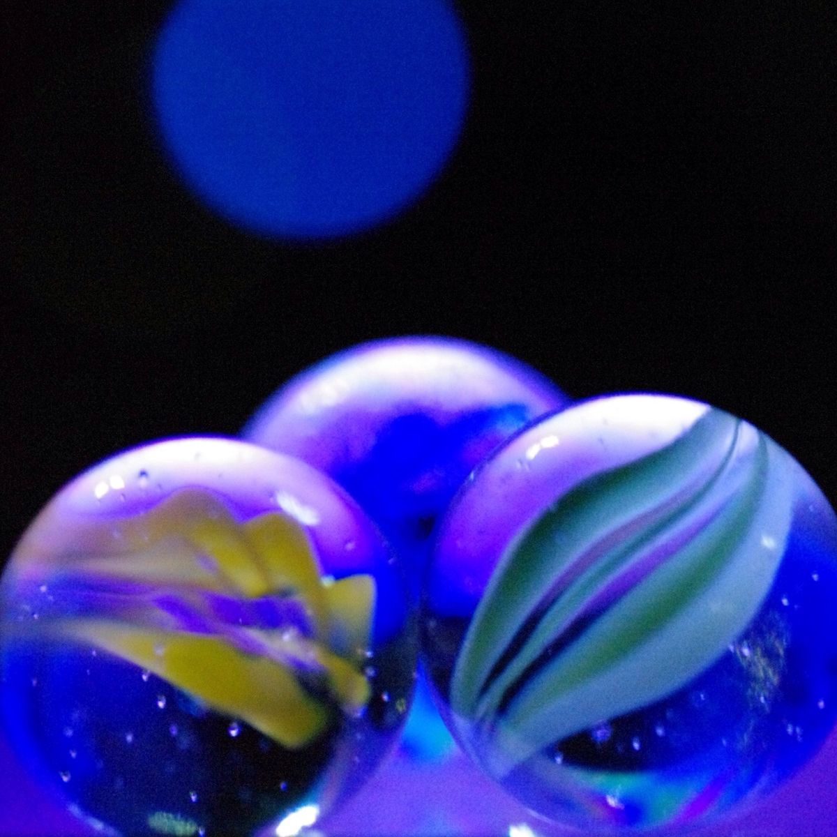 close up of marbles with reflection on glass against black background