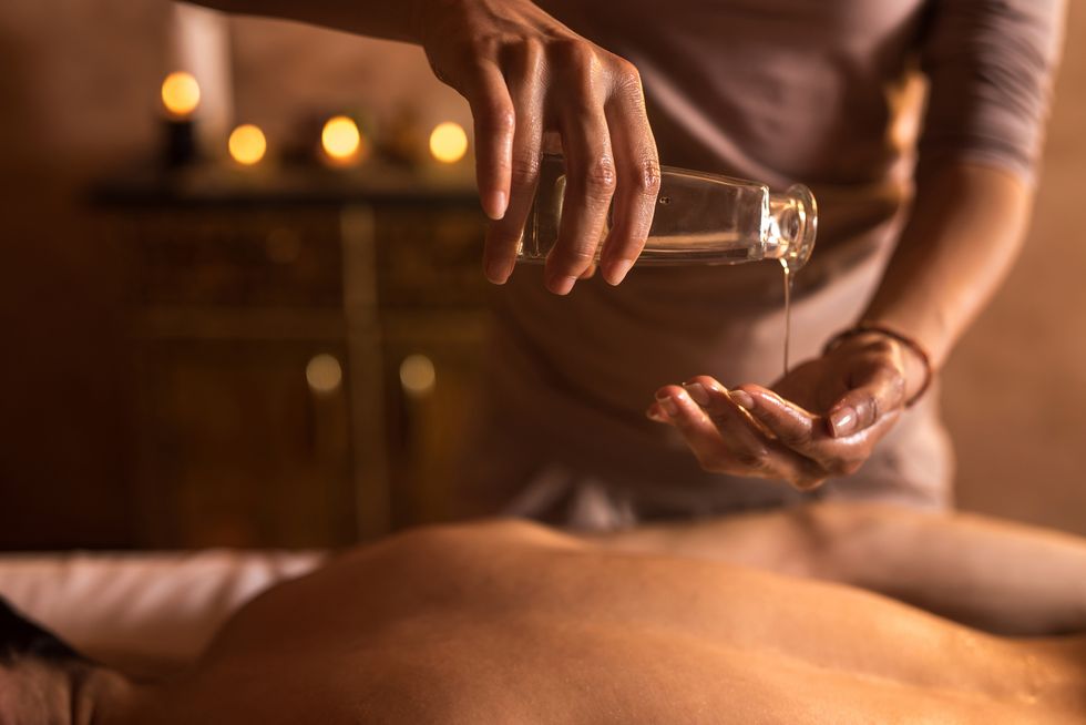 close up of massage therapist pouring massage oil in hand