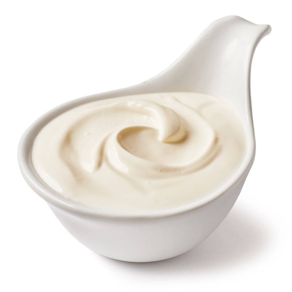 close up of mayonnaise in spoon against white background