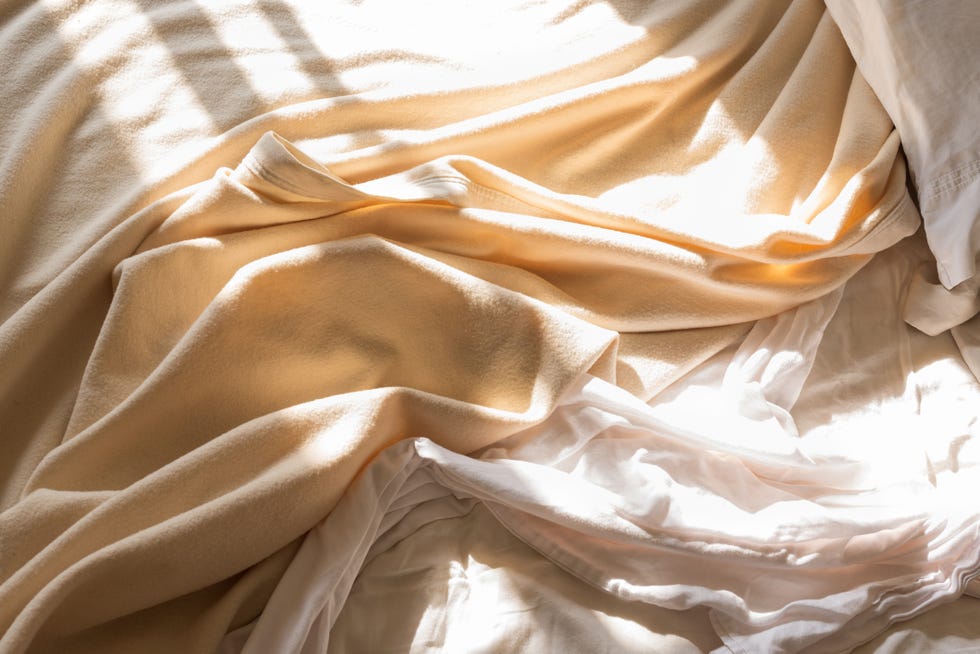 close up of messy bed sheet and blanket in morning sunlight