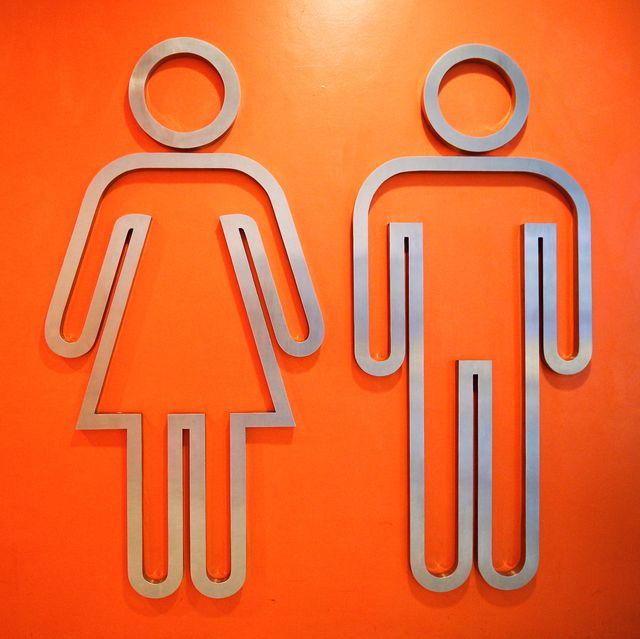 Close-Up Of Metallic Restroom Sign On Orange Wall