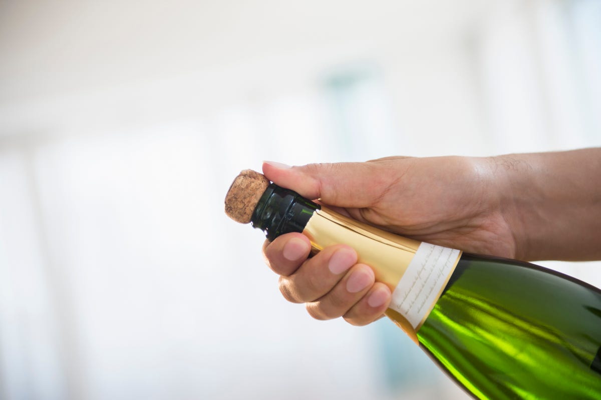 close up of mixed race man opening bottle of champagne