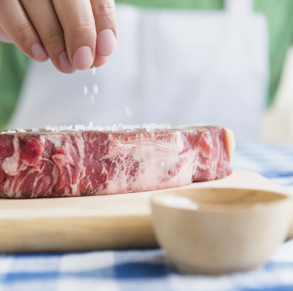 close up of mixed race man sprinkling salt on steak