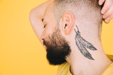 close up of neck tattoo on man against yellow background