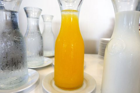 Close-Up Of Orange Juice Amidst Drinking Water And Milk In Bottles On Table