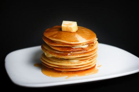 Close-Up Of Pancakes With Butter In Plate Against Black Background