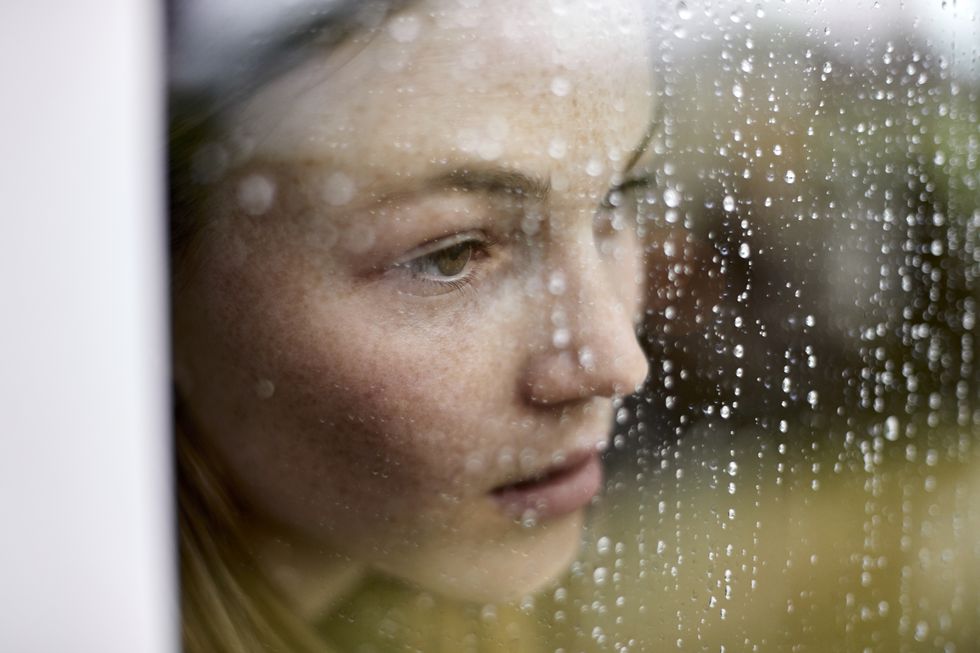 close up of pensive young woman looking out of window