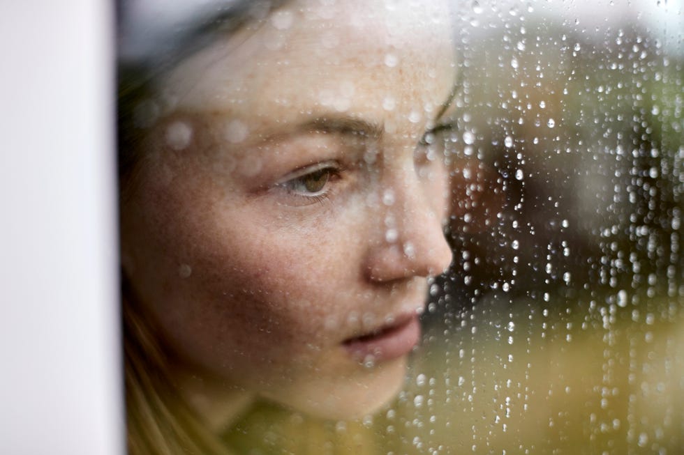 close up of pensive young woman looking out of window