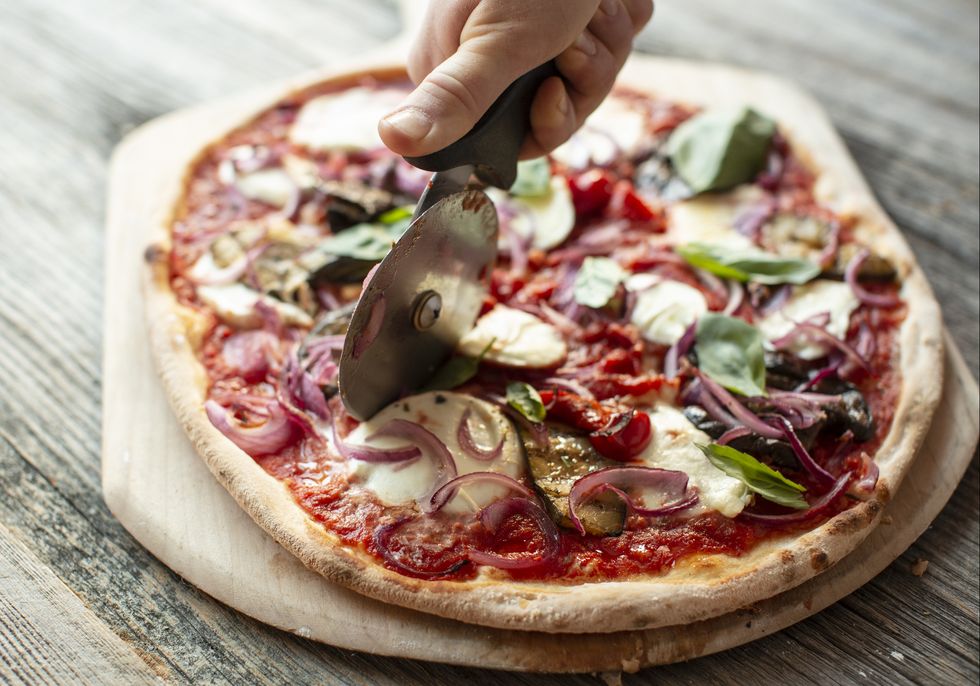 close up of pizza on table being cut
