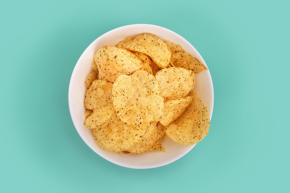 close up of potato chips in bowl on turquoise background