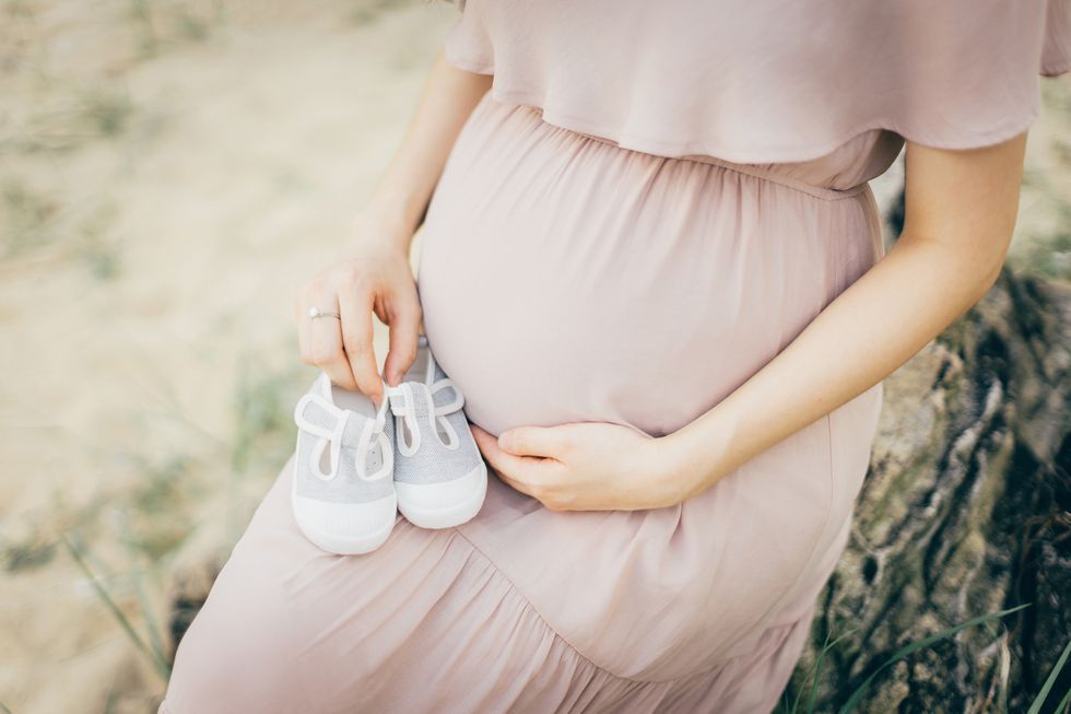 一個孕婦摸肚子、拿嬰兒鞋