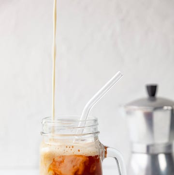 Close-up of 'proffee' (protein and coffee) in Mason Jar with reusable glass drinking straw on white background close up of 'proffee' protein and coffee in mason jar with reusable glass drinking straw on white background