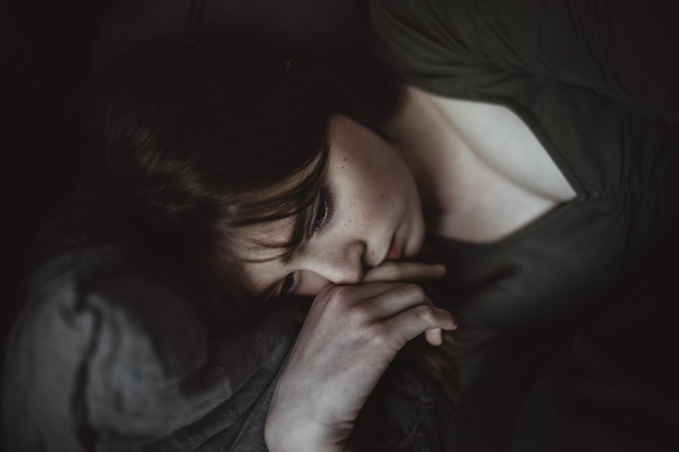 close up of sad woman lying on bed