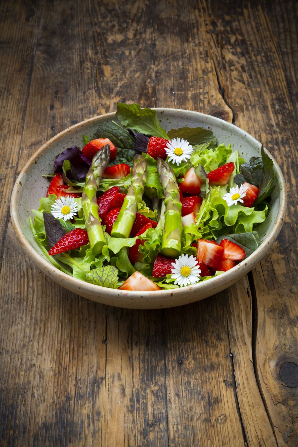 closeup of salad with green asparagus, strawberries and daisies