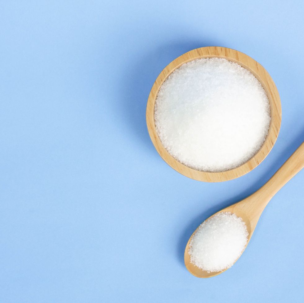Close-Up Of Salt In Bowl And Spoon Against Blue Background