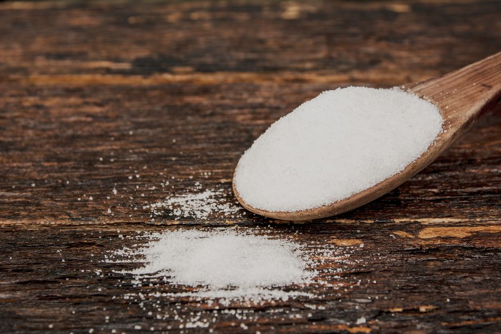 Close-Up Of Salt In Wooden Spoon Over Table