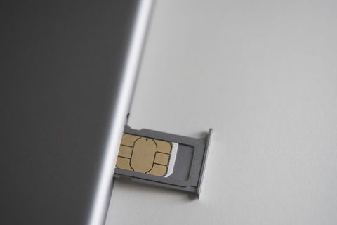 Close-up of sim card and mobile phone on white table