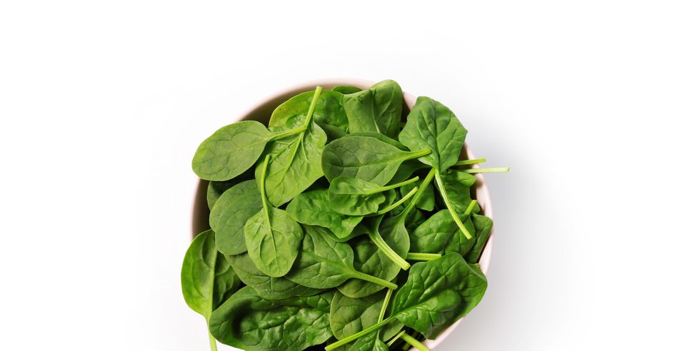 close up of spinach in bowl on white background