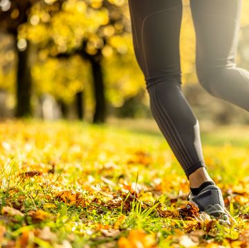 close up of sportswoman's legs during his exercise in autumn park.