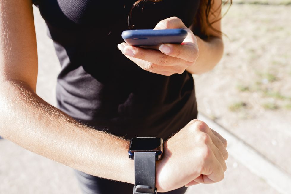 Close-up of sporty young woman using cell phone and smartwatch