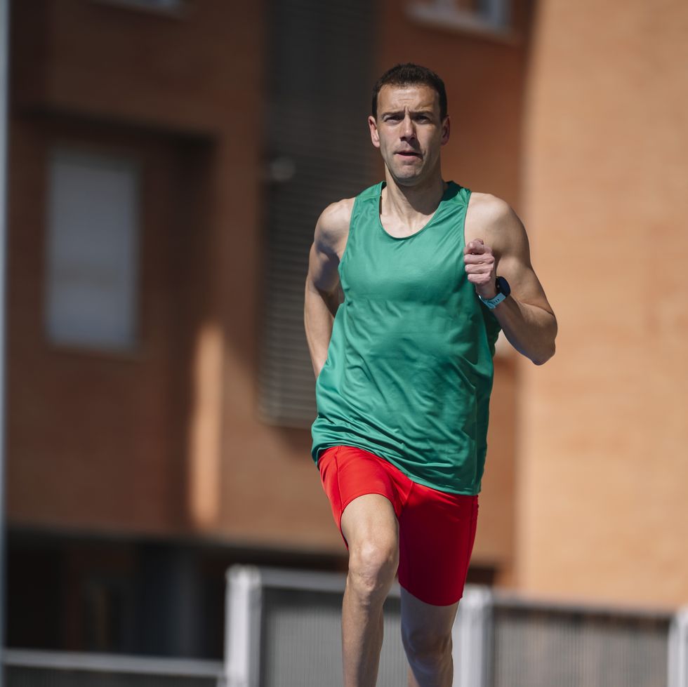 close up of sprinter mid stride, muscular legs propelling forward on blue track
