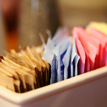 close up of sugar and sweetener packets in container at cafe