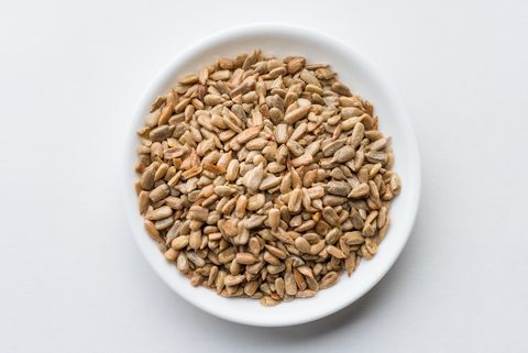 Close-Up Of Sunflower Seeds In Bowl Over White Background