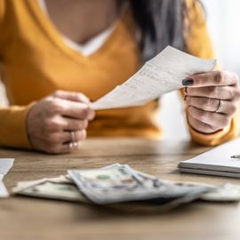 close up of the hands of a young woman checking shopping receipts.
