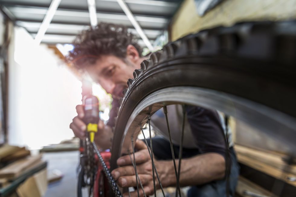 a mechanic lubing a bike chain