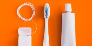 close up of toothbrush with toothpaste over orange background