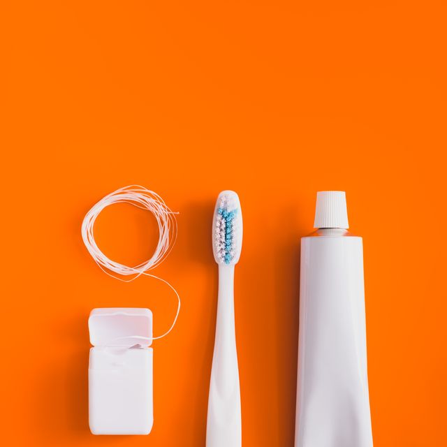 close up of toothbrush with toothpaste over orange background