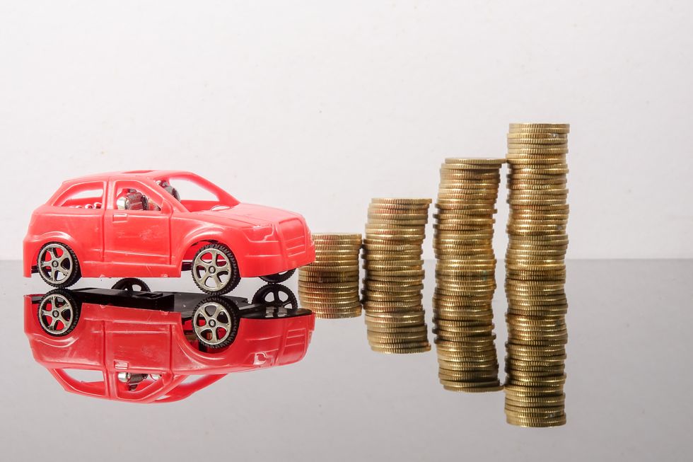 Close-Up Of Toy Cars And Coins On Table Against White Background
