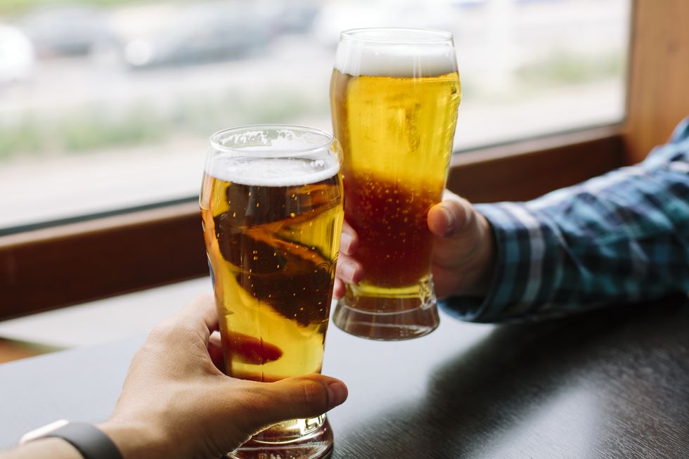 close up of two men's hands holding beer glasses