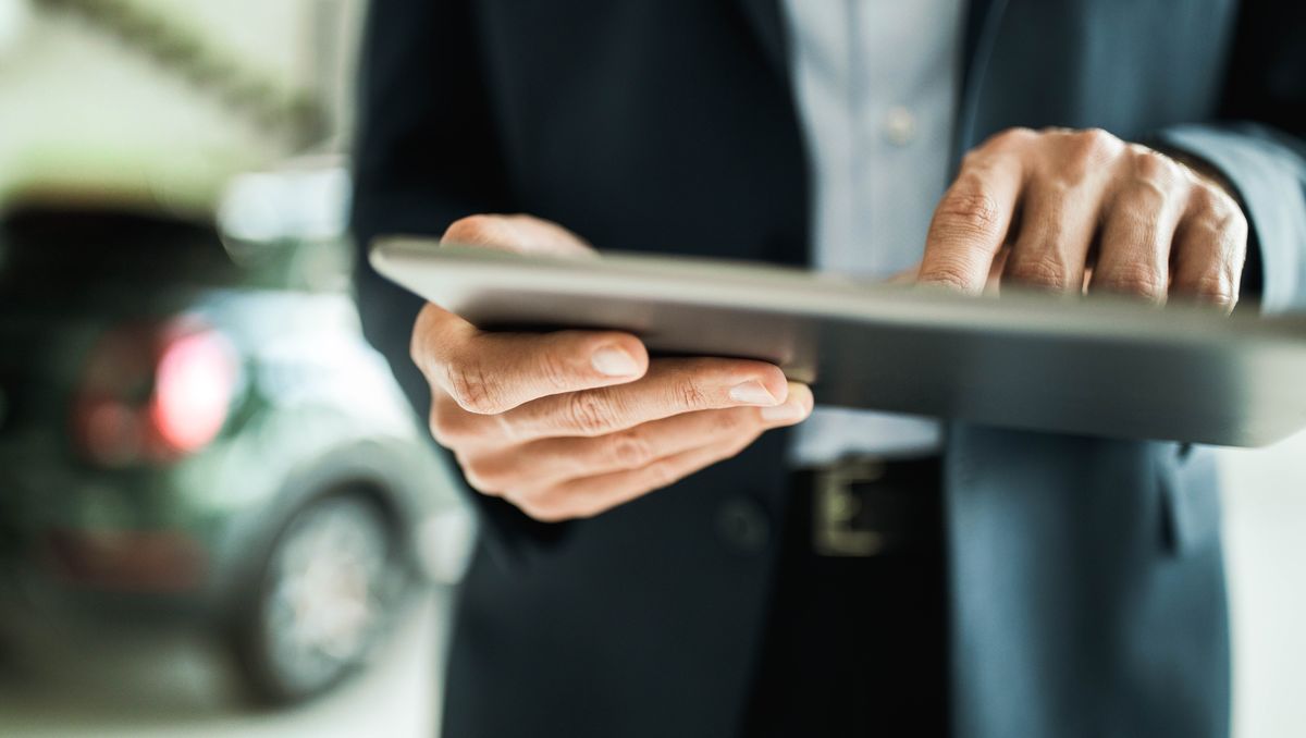 close up of unrecognizable car salesman using digital tablet