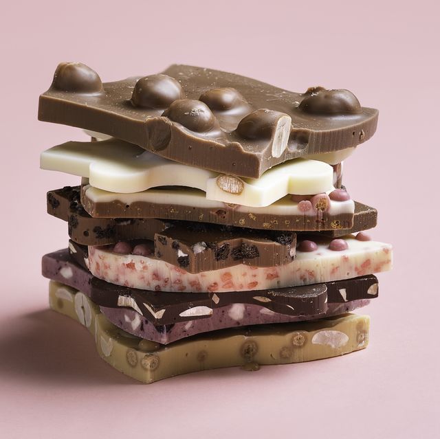 close up of various chocolates stacked on pink background