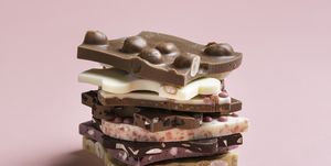 close up of various chocolates stacked on pink background