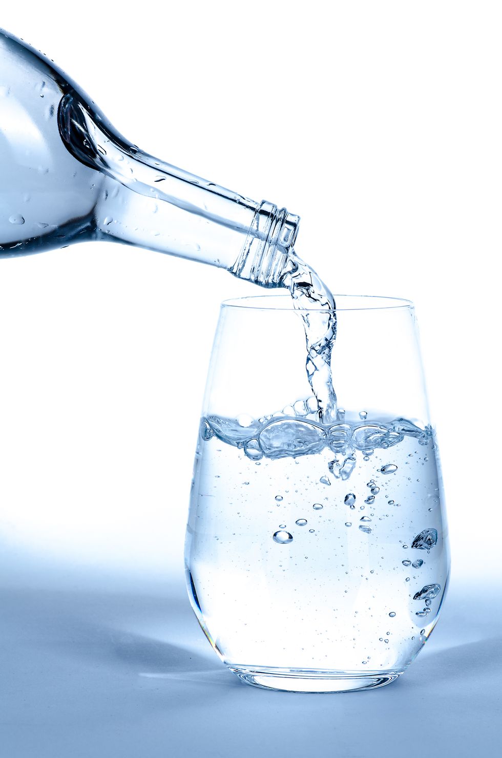 Close-Up Of Water Being Poured Into Glass Against White Background