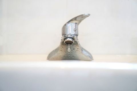 Close-Up Of Water Dripping From Faucet In Bathroom Sink