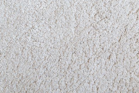 Close-up of white shaggy carpet texture background viewed from above.