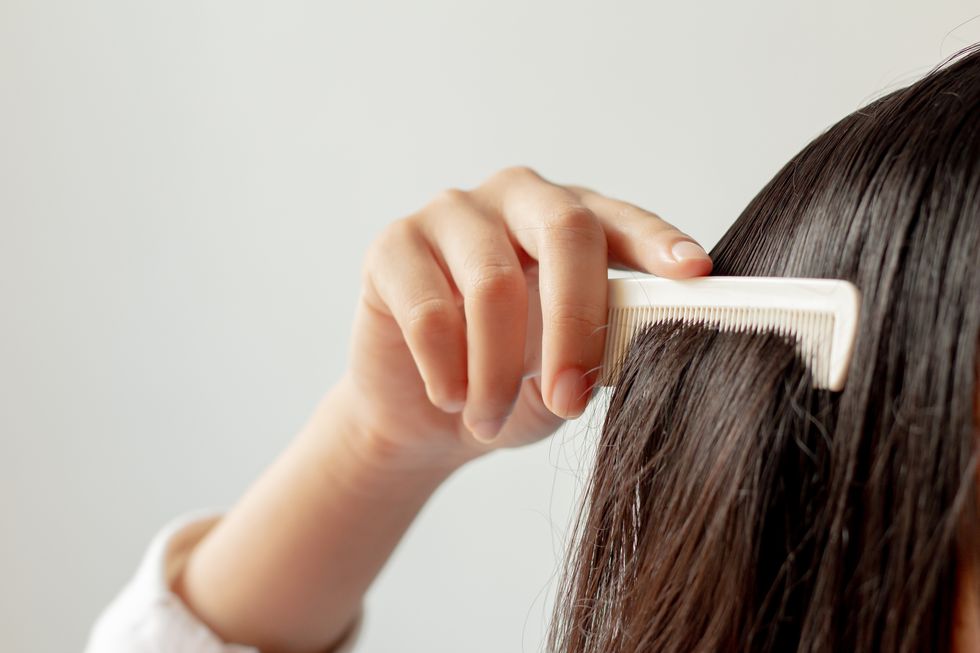 close up of woman combing hair against white background