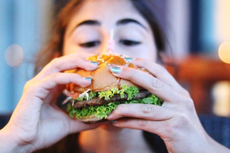 https://hips.hearstapps.com/hmg-prod/images/close-up-of-woman-eating-burger-royalty-free-image-1580230972.jpg?crop=1.00xw:0.753xh;0,0.247xh&resize=1200:*