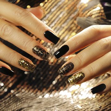hands with black and gold shimmery nail polish
