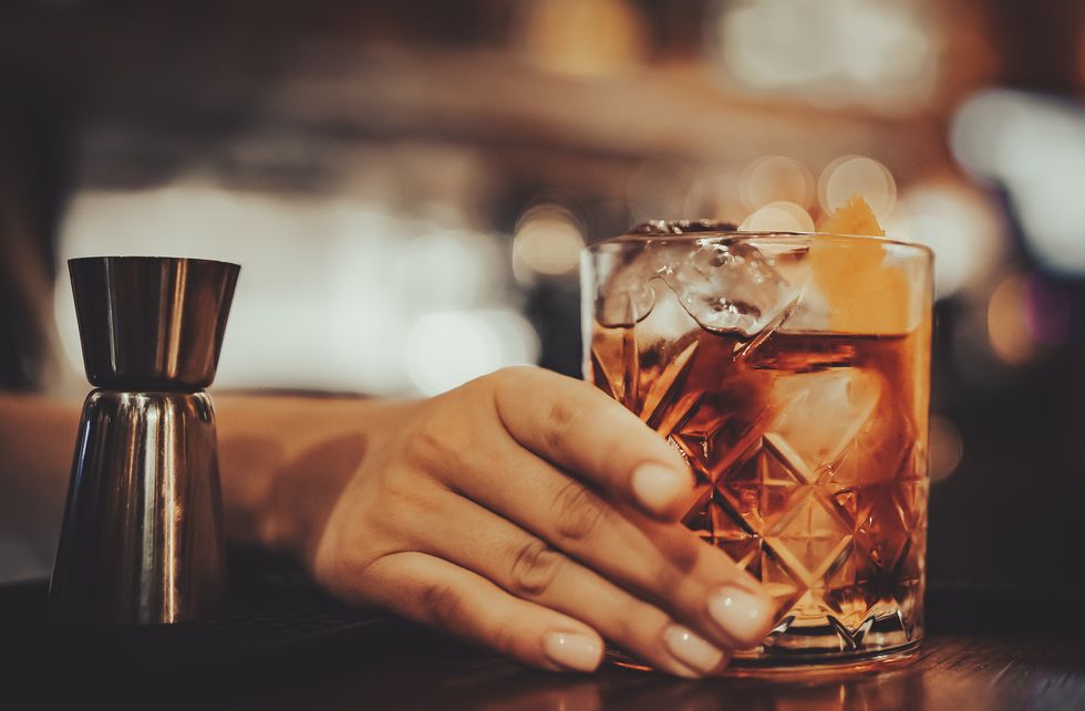 close up of woman hands holding glass with cocktail in bar