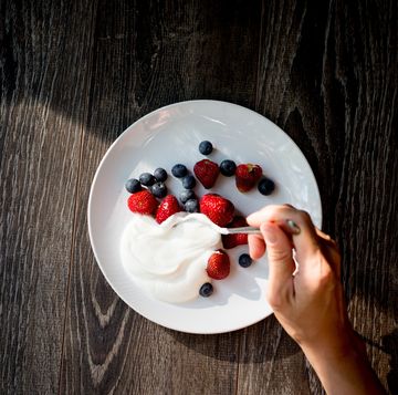 close up of woman hands with yogurt and berries on table