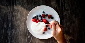 close up of woman hands with yogurt and berries on table