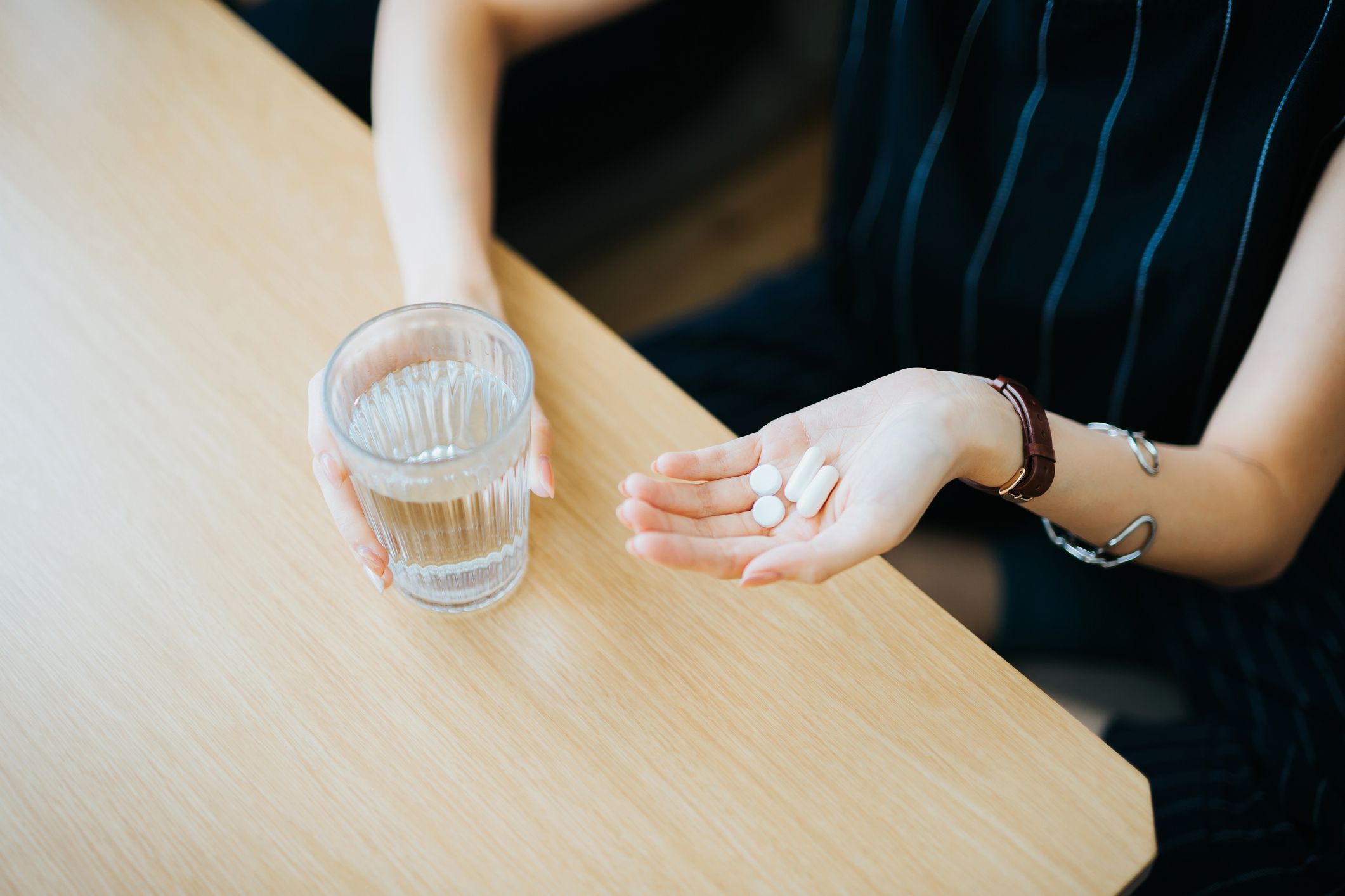 close up of woman holding a glass of water and medication in her hand